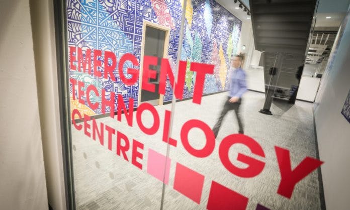 A close-up of a glass door in Abertay University,  printed with the words Emergent Technology Centre.