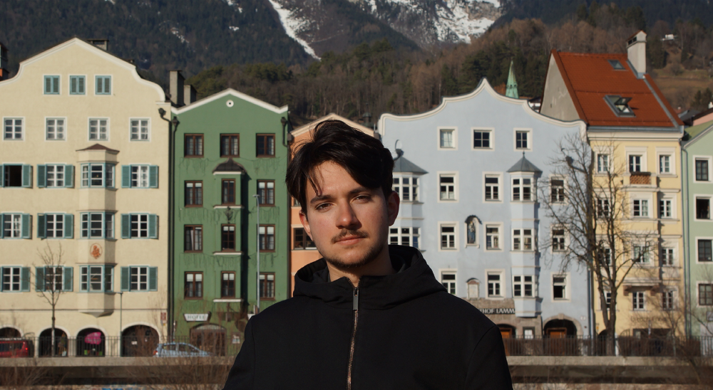 game designer Dimitrii Gruzdev of gaijin entertainment stands in front of a row of colourful houses.