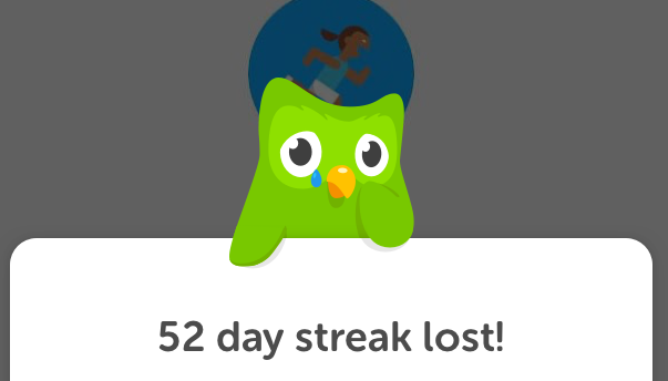 The Duolingo owl holds a sign saying '52 day streak lost!' and sheds a tear